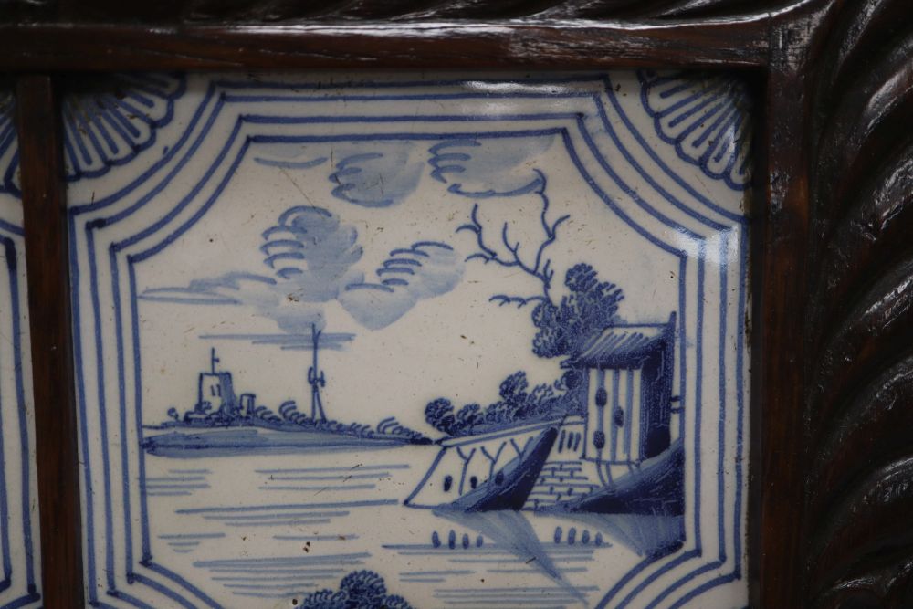 Four blue and white Delft tiles, housed in a carved oak frame, overall 35cm sq.